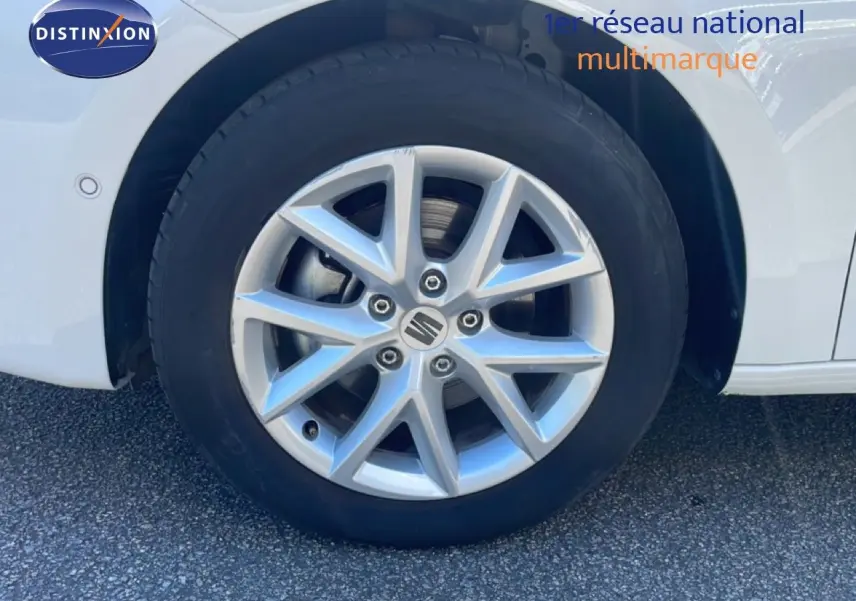 Gros plan sur la roue avant droite d'une SEAT LEON blanche avec jante alliage argentée à dix branches.