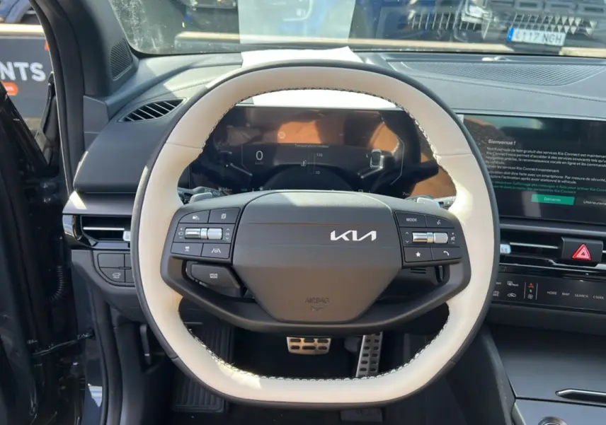 Vue intérieure centrée sur le volant cuir blanc et noir du Kia Sportage 2026 avec tableau de bord digital et écran tactile.