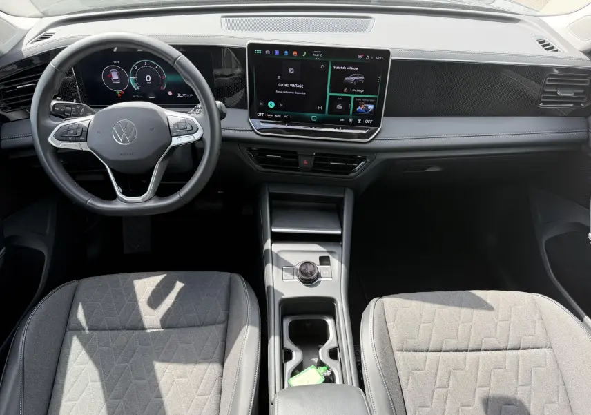 Vue intérieure avant du Volkswagen Tiguan 2025, tableau de bord noir avec écran tactile et volant multifonction cuir.