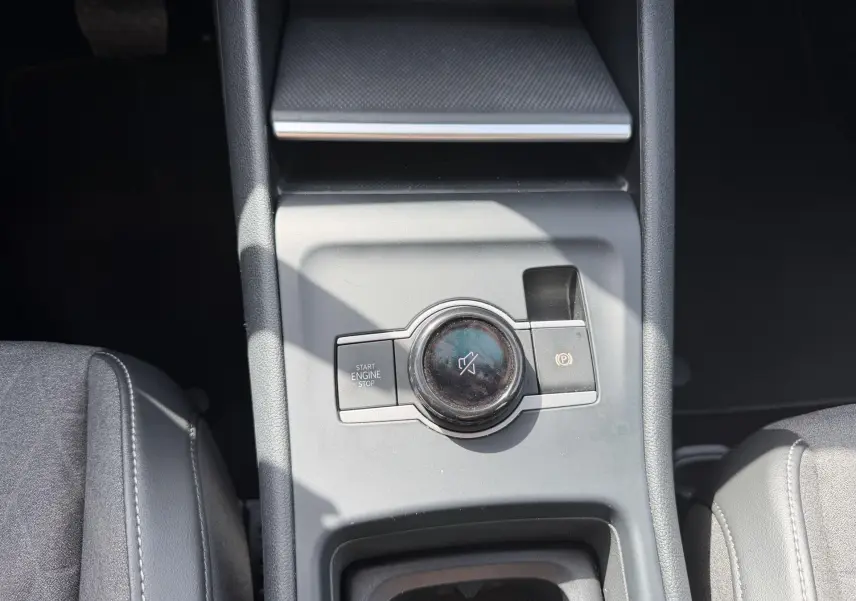 Gros plan sur la console centrale grise du Volkswagen Tiguan 2025, avec bouton start/stop et commande de volume silencieux.