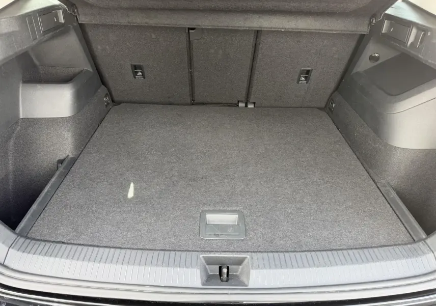 Coffre ouvert du Volkswagen Tiguan noir, vue de dessus montrant un espace de chargement propre et bien agencé.