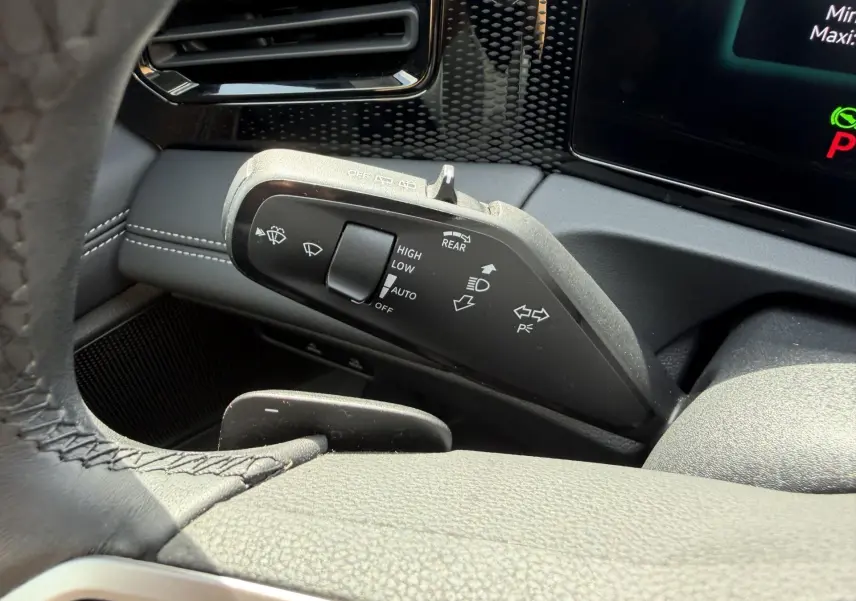 Gros plan sur la manette de commandes des essuie-glaces et feux du Volkswagen Tiguan 2025, intérieur noir avec coutures blanches.