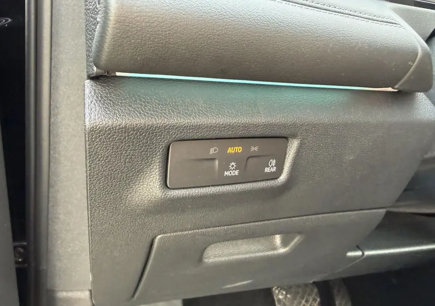 Gros plan sur le panneau de commande des feux avec mode automatique, à l'intérieur du Volkswagen Tiguan noir 2025.