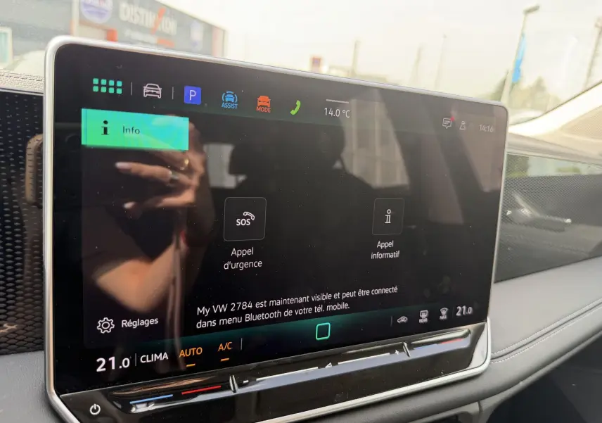 Écran tactile du tableau de bord du Volkswagen Tiguan 2025, affichant les options d'appel d'urgence et climatisation à 21°C.