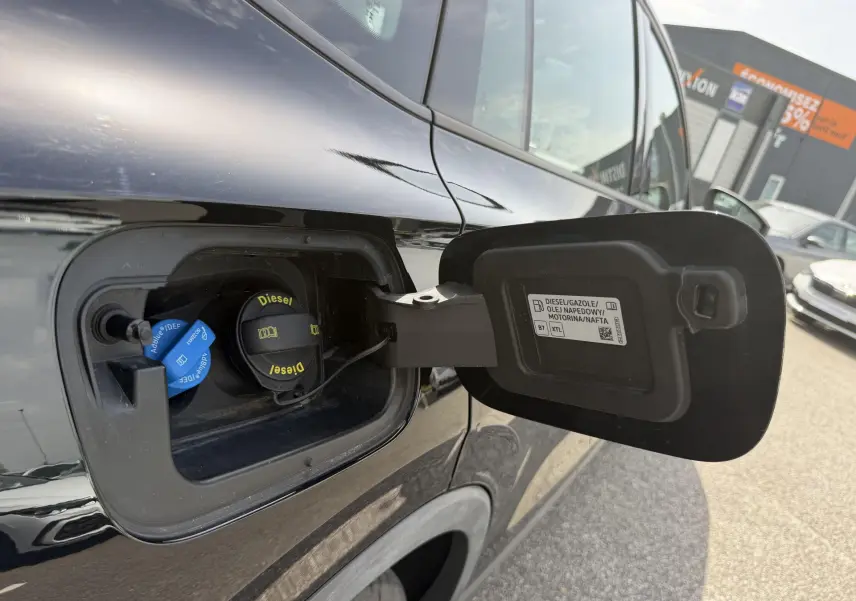 Vue rapprochée de la trappe à carburant ouverte côté gauche d’un Volkswagen Tiguan noir, bouchon diesel visible.