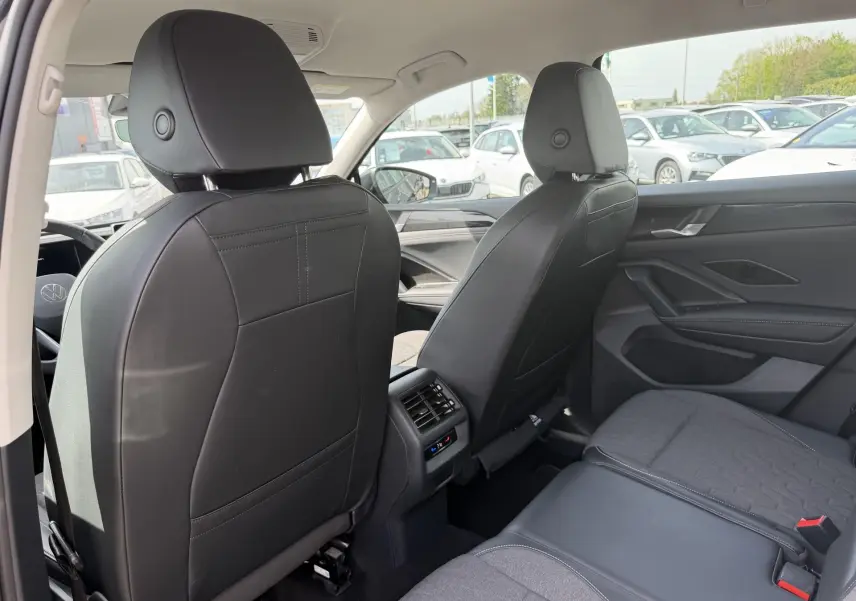 Vue arrière intérieure du Volkswagen Tiguan 2025 avec sièges noirs en cuir et tissu, et commandes de climatisation arrière visibles.