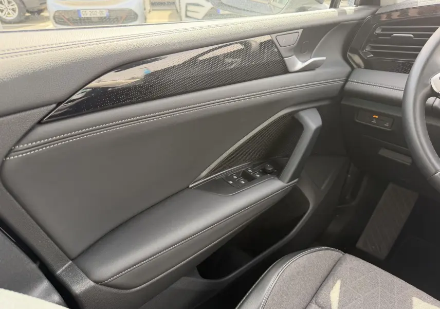 Vue intérieure côté gauche du Volkswagen Tiguan 2025, porte avec garniture noire et commandes électriques des vitres.