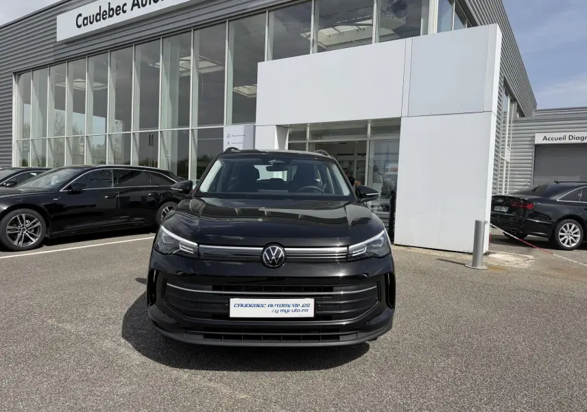 Volkswagen Tiguan noir vue de face, stationné devant un showroom avec calandre moderne et phares LED fins.