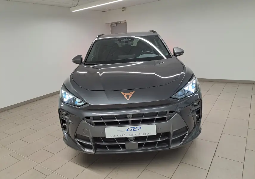 Vue avant d'une CUPRA TERRAMAR gris Timanfaya avec phares allumés dans un intérieur neutre.
