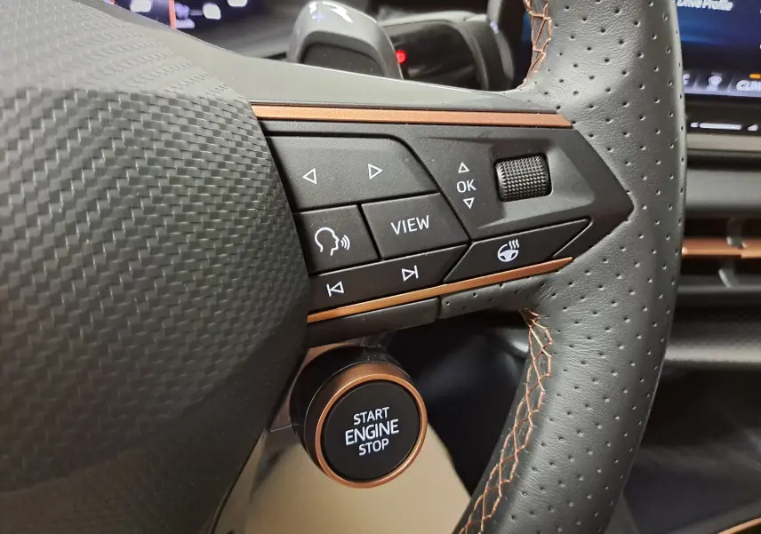 Gros plan sur le volant perforé noir avec surpiqûres cuivrées et bouton Start Engine Stop du CUPRA TERRAMAR 2025.