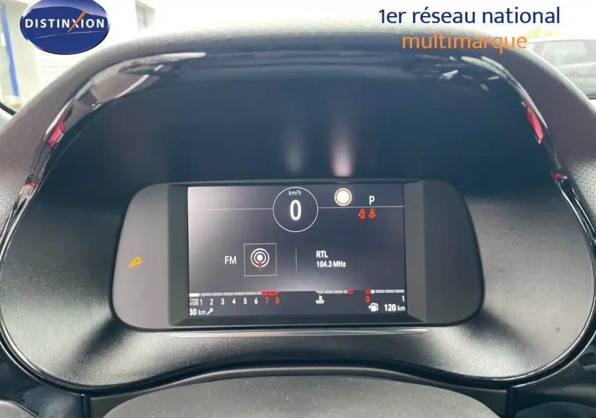 Tableau de bord numérique de l'Opel Corsa blanc 2022, affichant vitesse à 0 km/h et radio RTL 104.3 MHz.