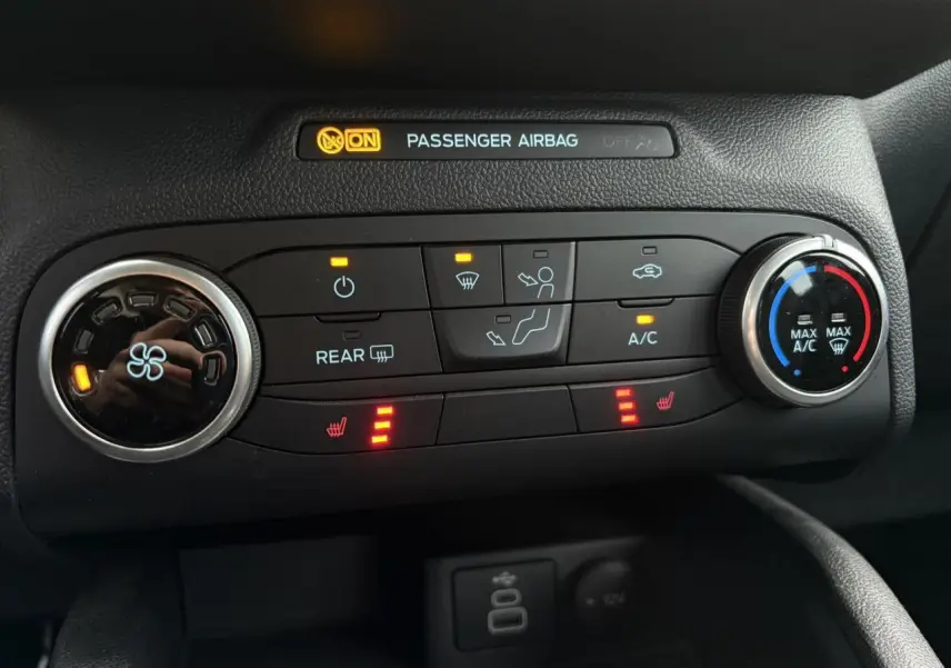 Gros plan sur la console de climatisation du Ford Kuga noir Obsidien 2024 avec commandes chauffantes et ventilation active.