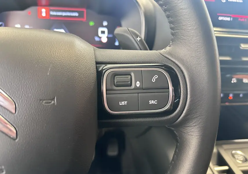 Gros plan sur les commandes à droite du volant cuir du Citroën C5 Aircross 2024 gris Artense, affichage numérique en arrière-plan.