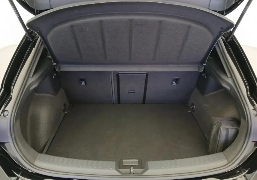 Coffre ouvert vu de l'arrière d'une CUPRA Leon Noir Minuit avec intérieur de coffre spacieux et habillage sombre.