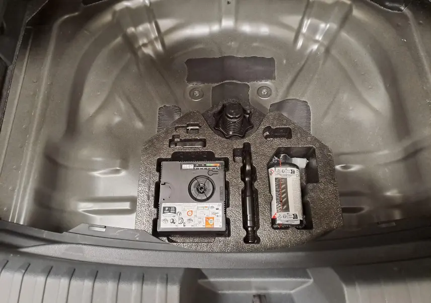 Coffre ouvert vue de dessus montrant le compartiment de rangement avec kit de réparation sur CUPRA Leon Noir Minuit 2025.