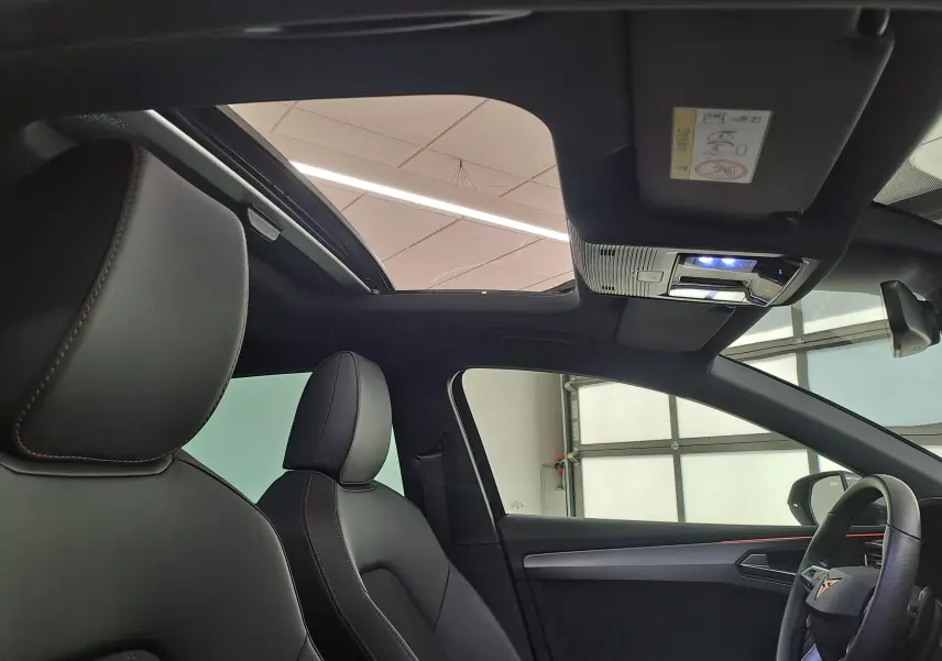 Vue intérieure côté conducteur du CUPRA Leon 2025 avec toit ouvrant panoramique et sièges en cuir noir.