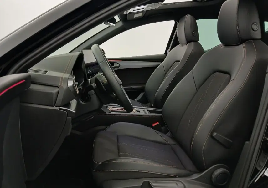 Vue intérieure côté conducteur de la CUPRA Leon 2025 avec sièges noirs, coutures contrastées et toit ouvrant panoramique.