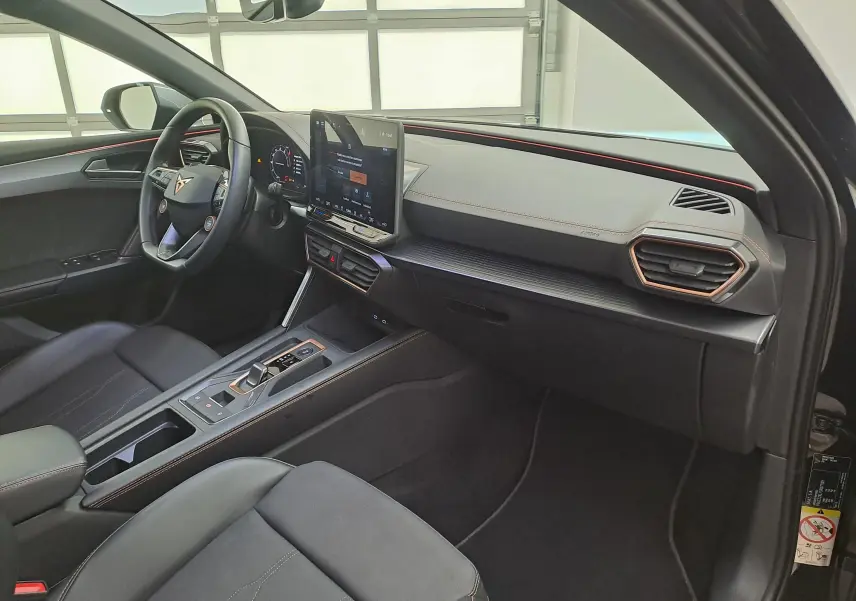 Vue intérieure côté conducteur de la CUPRA Leon 2025 noir minuit, avec tableau de bord moderne et écran tactile central.