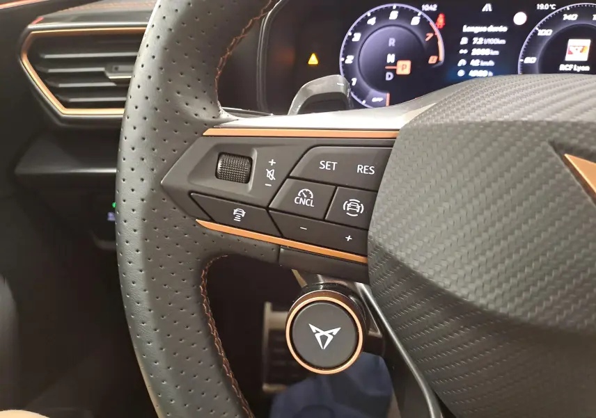 Gros plan sur le volant perforé noir avec surpiqûres cuivrées et commandes multifonctions du CUPRA Leon 2025.