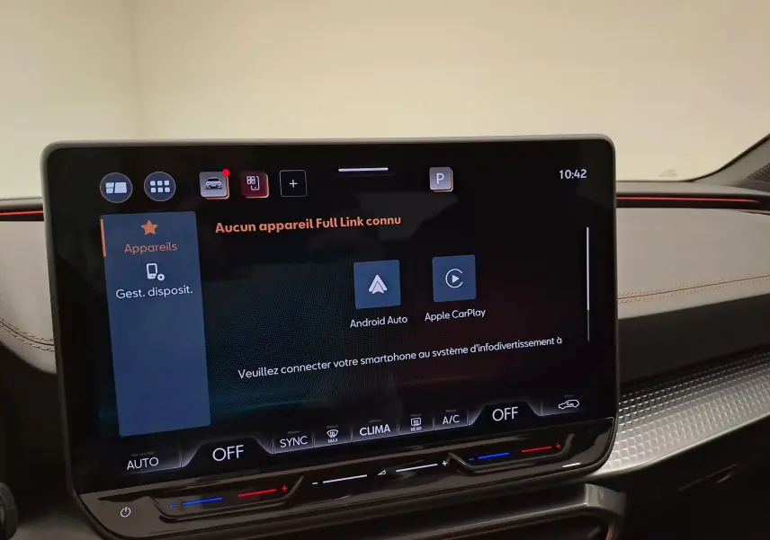 Écran tactile central de la CUPRA Leon 2025 affichant les options Android Auto et Apple CarPlay, avec tableau de bord noir et surpiqûres orange.