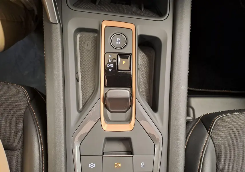Vue plongeante sur la console centrale de la CUPRA Leon 2025, avec commandes de boîte auto et surpiqûres orange visibles.