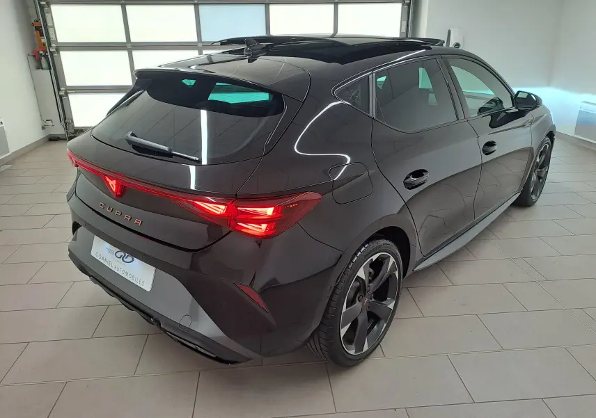 Vue 3/4 arrière droite d'une CUPRA Leon Noir Minuit avec toit ouvrant panoramique et feux arrière Matrix LED allumés.