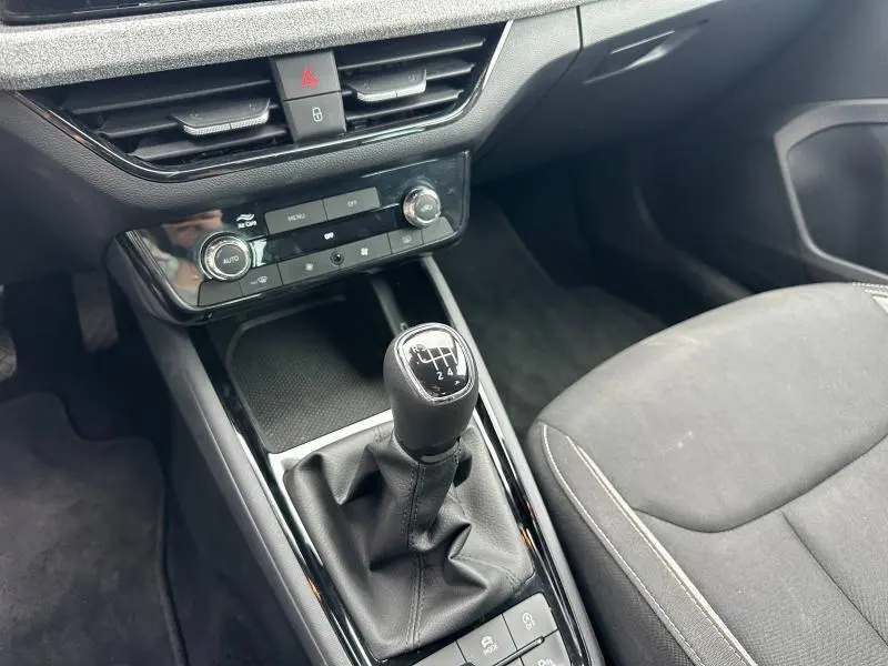 Gros plan sur la console centrale noire avec levier de vitesses manuel et sièges tissu gris dans une Skoda Scala 2025.
