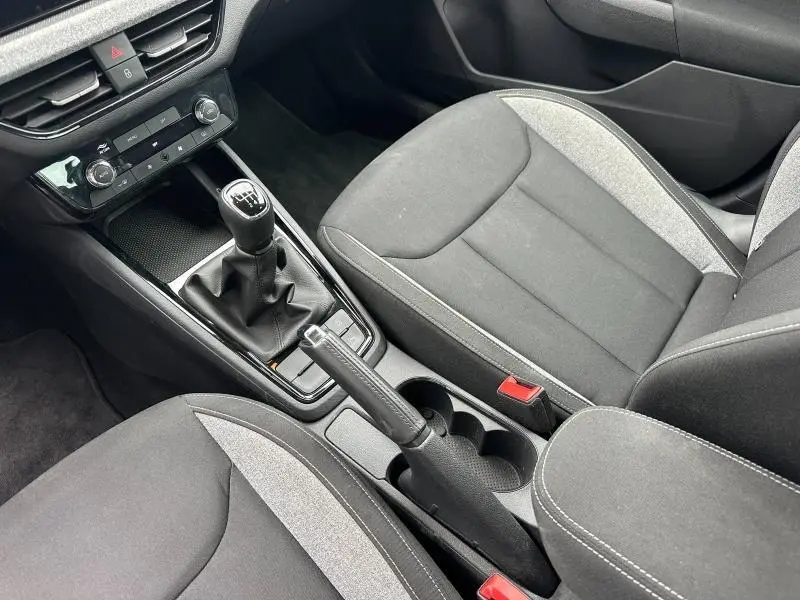 Vue intérieure centrée sur la console centrale et sièges avant en tissu noir et gris du Skoda Scala 2025.