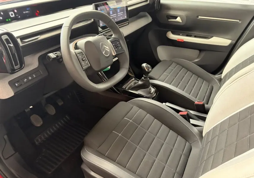 Intérieur de la Citroën C3 Turbo 100 BVM6 2025 vu côté conducteur, sièges bi-ton noirs et gris, volant cuir multifonctions.