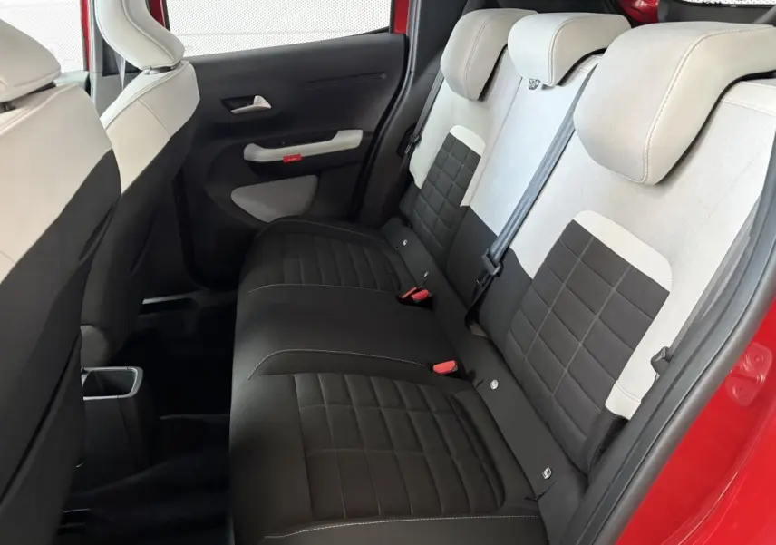 Vue intérieure côté arrière droit de la banquette arrière bicolore noire et beige d'une Citroën C3 rouge 2025.