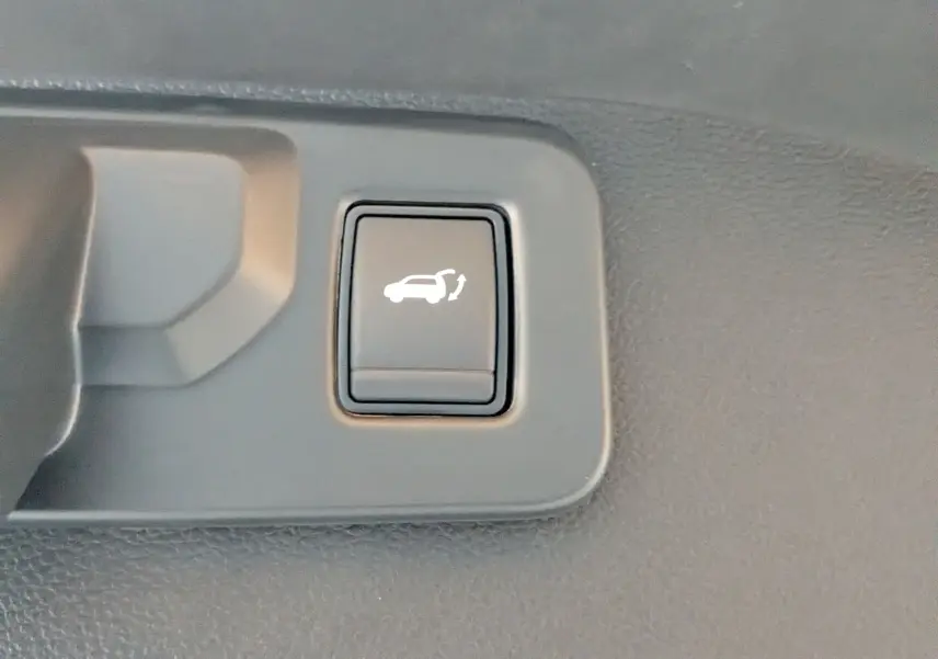 Bouton intérieur noir avec symbole blanc d'ouverture du hayon, situé sur la garniture du coffre du Renault Austral E-Tech.