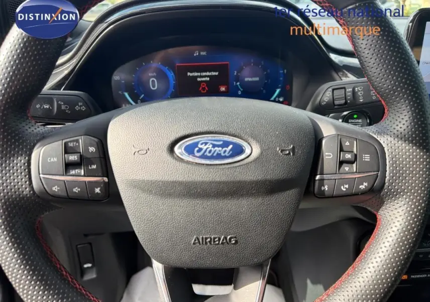 Vue rapprochée du volant perforé avec surpiqûres rouges du Ford Puma 2022, tableau de bord numérique visible.