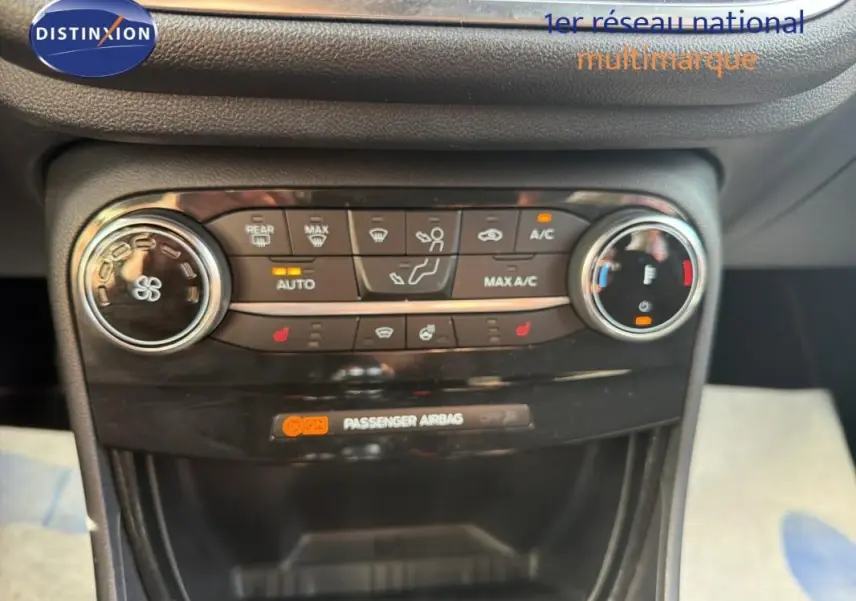 Vue rapprochée du tableau de bord central du Ford Puma gris foncé, montrant les commandes de climatisation et l'indicateur airbag passager.
