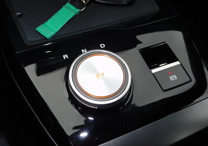 Gros plan sur la molette de sélection de vitesse et frein à main électronique du MG4 électrique noir brillant.