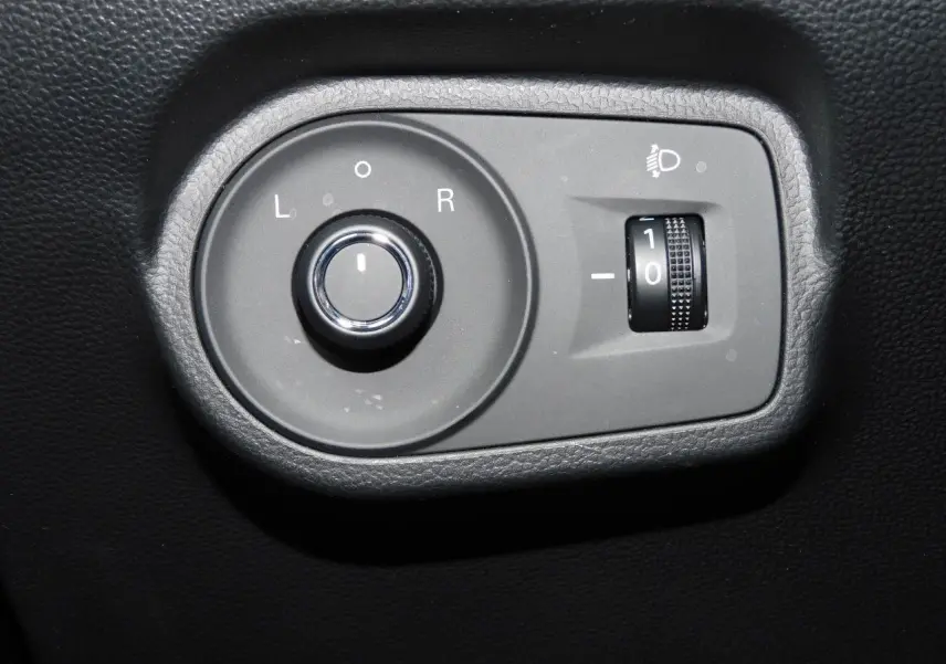 Gros plan sur les commandes de réglage des rétroviseurs et de l'éclairage du tableau de bord du MG MOTOR MG4 blanc 2023.