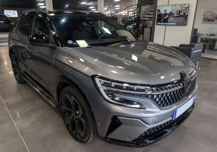 Renault Austral E-Tech hybride gris schiste avec toit noir, vue 3/4 avant droit en intérieur showroom.