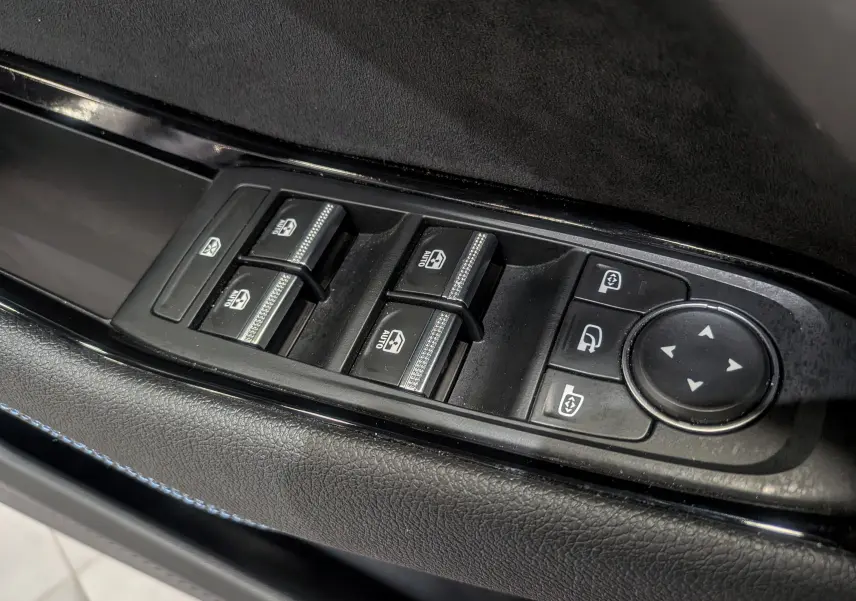 Vue rapprochée des commandes de lève-vitres et réglage des rétroviseurs sur la porte côté conducteur du Renault Austral gris Schiste.