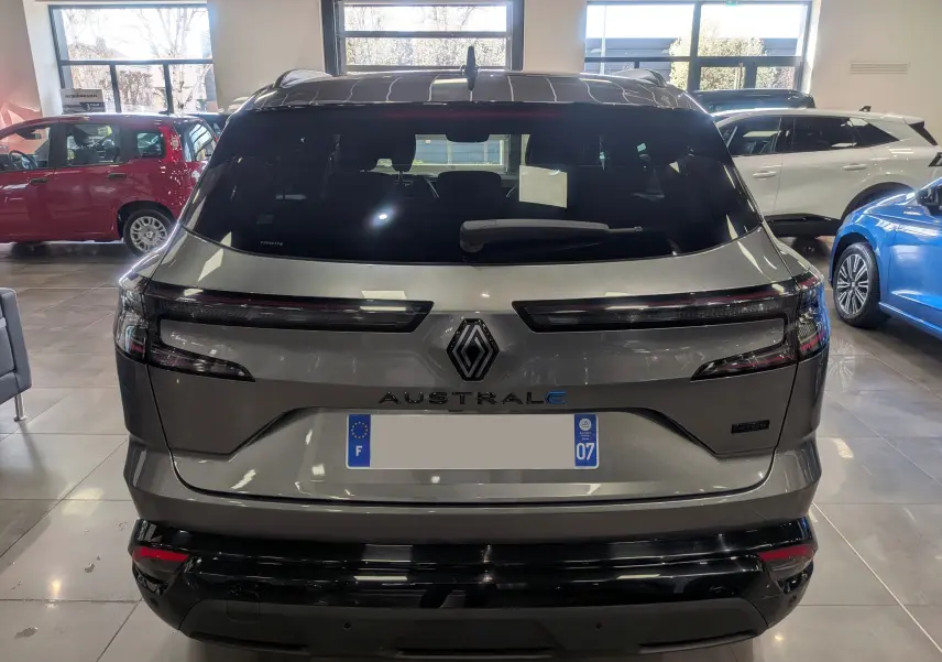 Vue arrière d’un Renault Austral E-Tech hybride 2023 gris schiste avec toit noir en showroom, détails lumineux et logo central visibles.