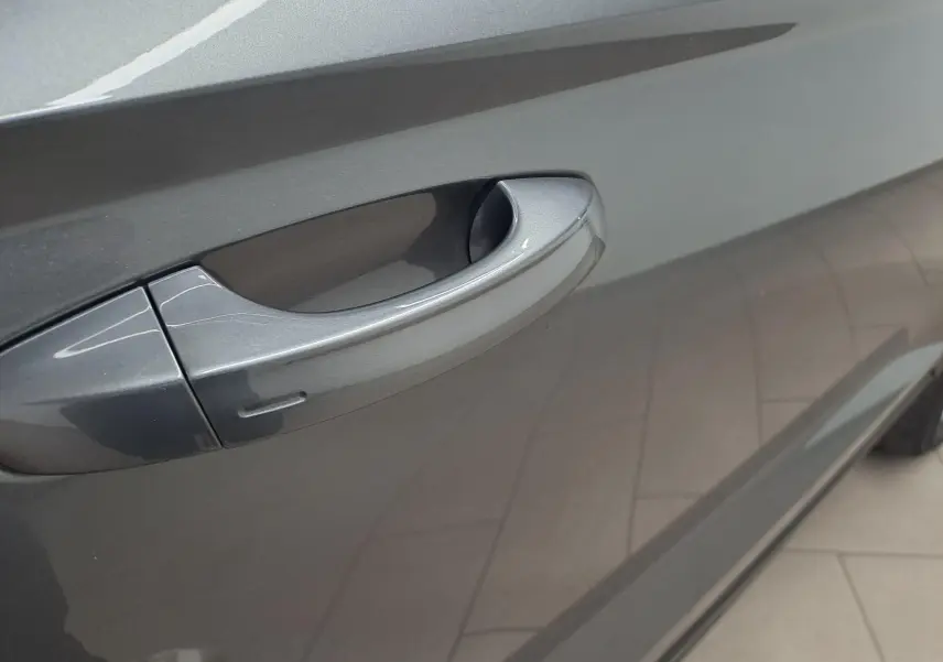 Gros plan sur la poignée de porte côté droit du SEAT Ateca 2023 en peinture métallisée gris graphite.