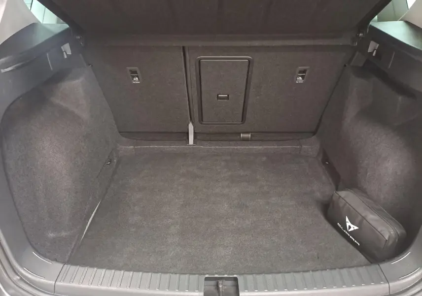 Coffre ouvert du SEAT Ateca gris graphite 2023, montrant un espace de chargement vide avec une trousse noire sur la droite.