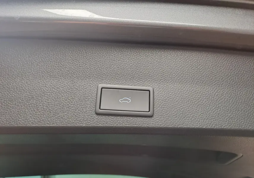 Bouton d'ouverture électrique du coffre sur la garniture intérieure du hayon d'un SEAT Ateca gris graphite.