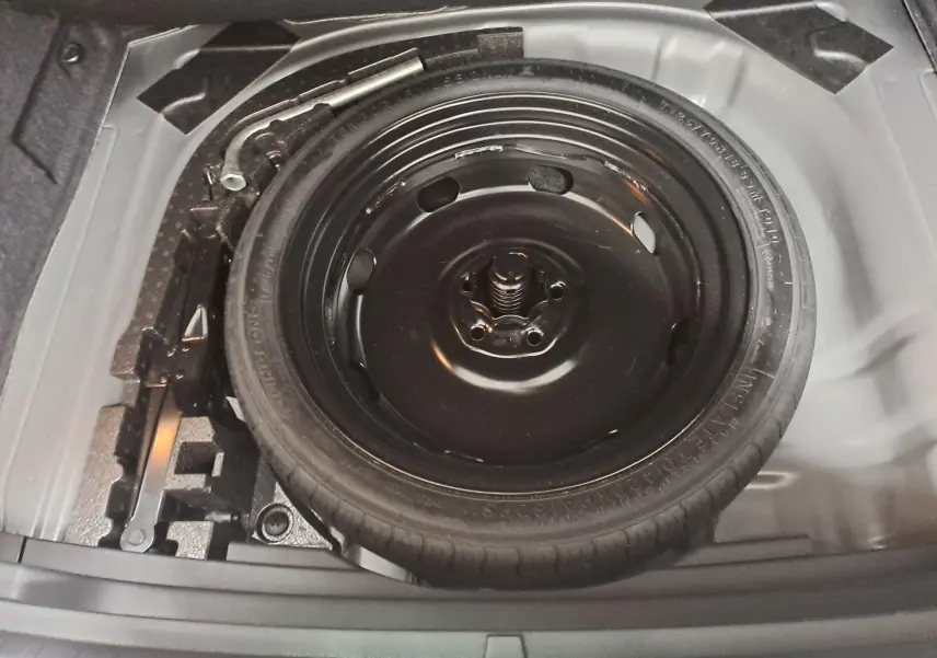 Vue rapprochée de la roue de secours noire et des outils dans le coffre du SEAT Ateca Gris Graphite 2023.