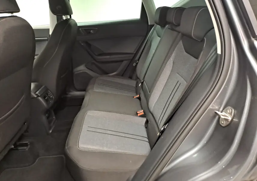 Vue intérieure côté droit des sièges arrière du SEAT Ateca 2023 gris graphite, avec sellerie tissu bicolore et ceintures visibles.