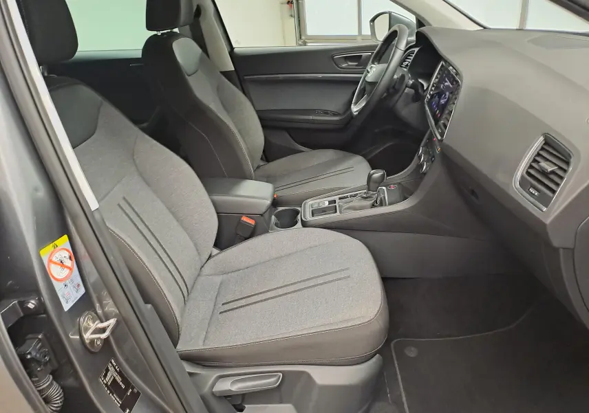 Vue intérieure côté conducteur du SEAT Ateca 2023 gris graphite, sièges tissu gris et console centrale avec boîte auto DSG7.