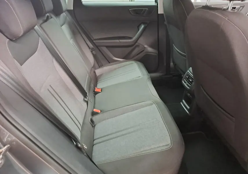 Vue intérieure du siège arrière côté gauche du SEAT Ateca 2023 avec sellerie tissu gris et ceintures de sécurité visibles.
