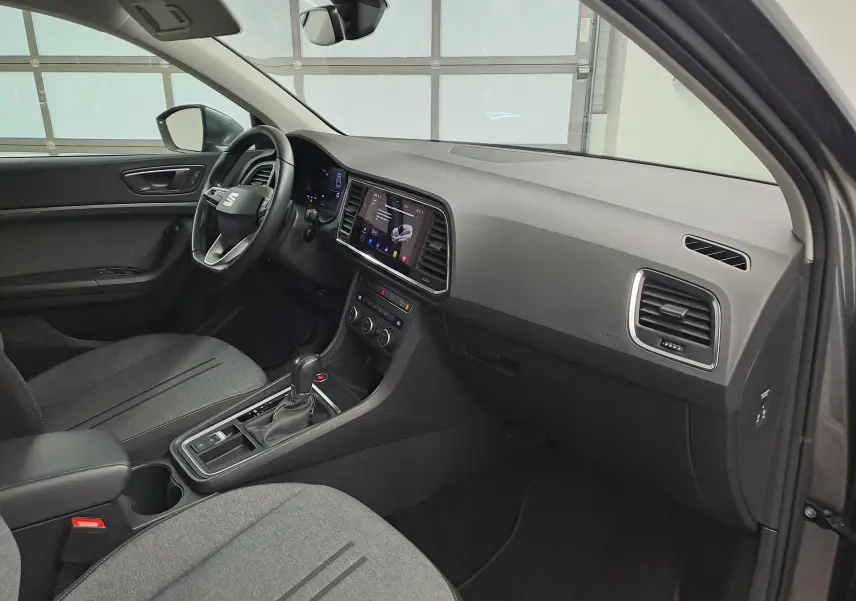 Vue intérieure côté conducteur du SEAT Ateca 2023 avec tableau de bord noir et sièges gris tissu.