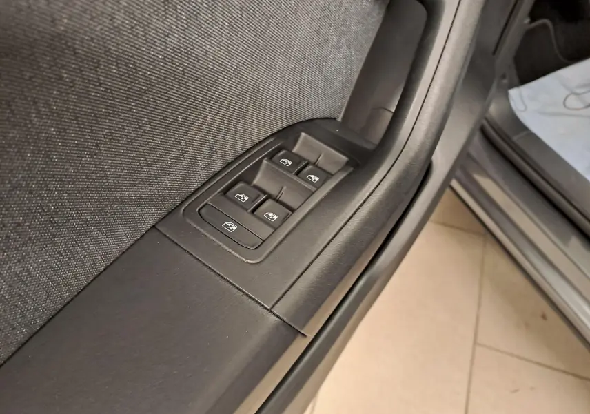 Gros plan sur les commandes des vitres électriques côté conducteur du SEAT Ateca 2023 gris graphite, intérieur noir.