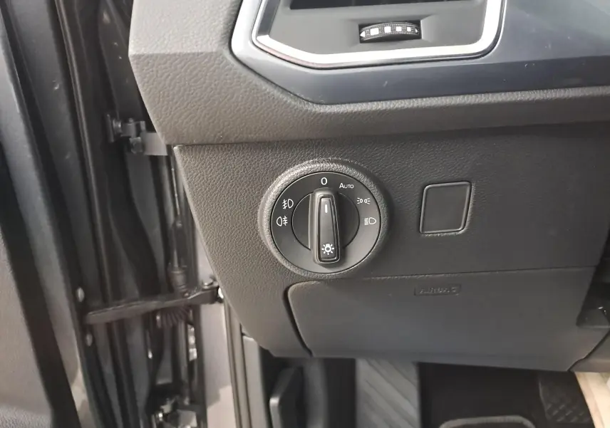 Gros plan sur la commande des phares à gauche du tableau de bord du SEAT Ateca gris graphite 2023.