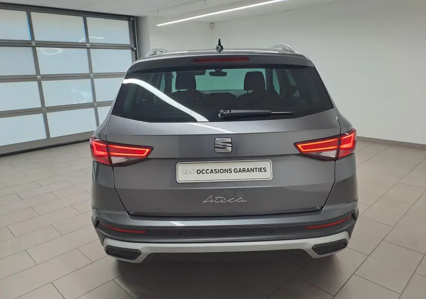 Vue arrière du SEAT Ateca gris graphite 2023 avec feux LED allumés dans un showroom intérieur.