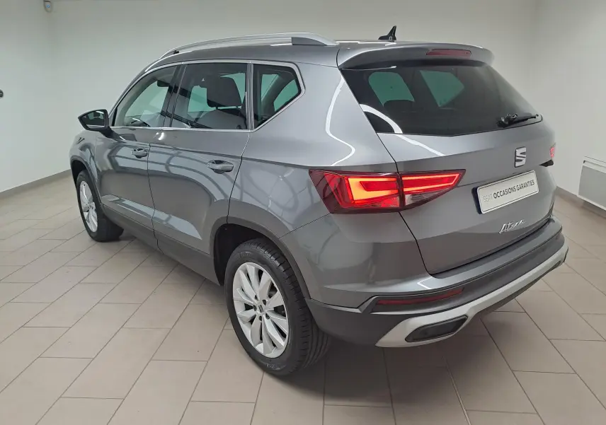 Vue 3/4 arrière droite du SEAT Ateca gris graphite 2023 avec feux arrière allumés et jantes alliage.